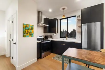 a kitchen with black and white cabinets and a table at Private Studio - Stylish Cozy & Central in San Diego