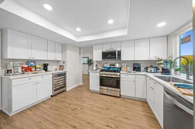 a large kitchen with white cabinets and wooden floors at Entire Private Home with 4 Bedrooms 2 Bathrooms Garage, Pool, King Bed, Gated Yard in Rancho Penasquitos, Available Now in San Diego
