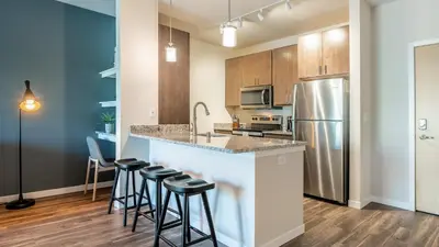 a kitchen with a counter with stools and a refrigerator at Landing Stylish 1BD Yoga Studio Game Room in Murrieta
