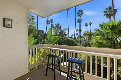 a balcony with two stools and palm trees at G101 - Twin View Villa in Oceanside