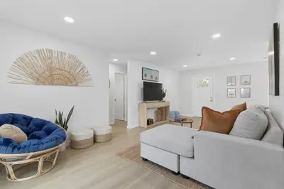 a white living room with a couch and a tv at One Block to Beach 4BR Game Room and Parking in San Diego