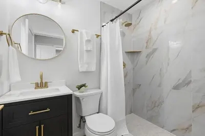 a bathroom with a toilet and a sink and a mirror at One Block to Beach 4BR Game Room and Parking in San Diego