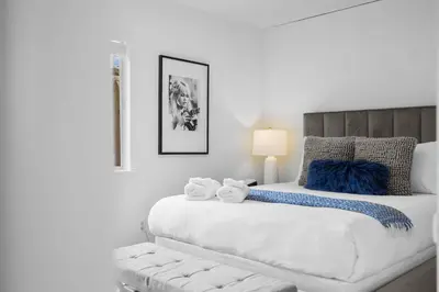 a white bedroom with a large bed with blue accents at Ocean Paradise | Patio, Parking, BBQ, Location! in San Diego