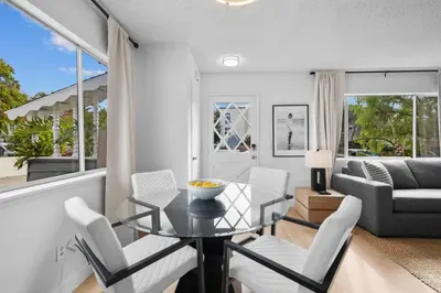 a living room with a glass table and white chairs at Ocean Paradise | Patio, Parking, BBQ, Location! in San Diego