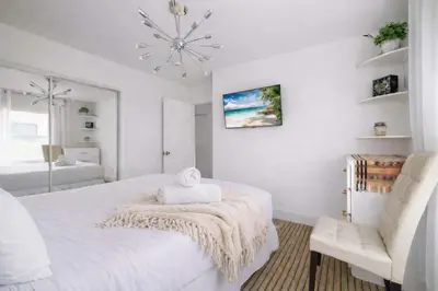 a white bedroom with a bed and a chandelier at Central Location Cozy Home Villa in San Diego