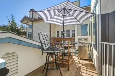 a patio with a table and chairs under an umbrella at Beach Getaway Apt - Walk to Sand & Bay in San Diego