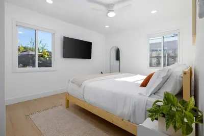 a white bedroom with a bed and a flat screen tv at Carlsbad Bungalow Large Backyard in Carlsbad