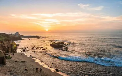 a group of people standing on a beach with the ocean at Entire Building Sleeps 20 I Little Italy in San Diego