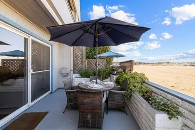 a table and chairs with an umbrella on a patio at Bayfront Getaway | 2BR Retreat w/ Patio & BBQ, Steps to Sand in San Diego