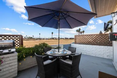 a table and chairs with an umbrella on a patio at Bayfront Getaway | 2BR Retreat w/ Patio & BBQ, Steps to Sand in San Diego
