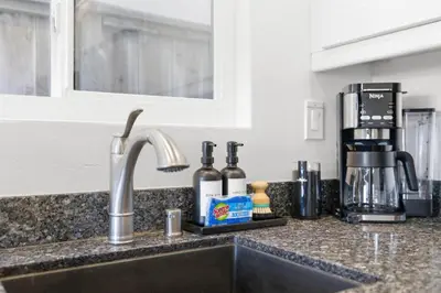 a kitchen counter with a sink with wine bottles at Bayfront Getaway | 2BR Retreat w/ Patio & BBQ, Steps to Sand in San Diego