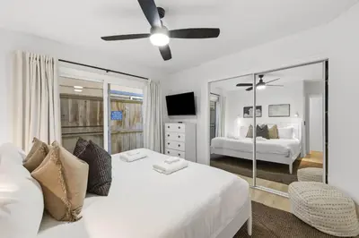 a white bedroom with a bed and a mirror at Bayfront Getaway | 2BR Retreat w/ Patio & BBQ, Steps to Sand in San Diego