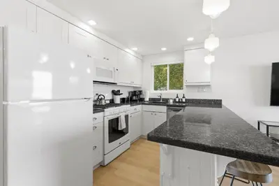 a kitchen with white cabinets and a black counter top at Cozy 2BR Bayfront Home | Patio + Water Views in Mission Beach in San Diego