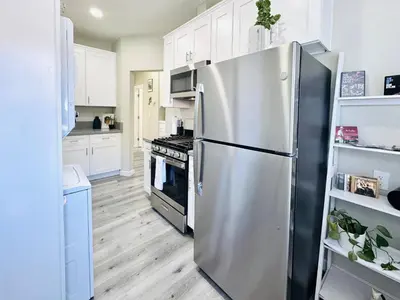 a stainless steel refrigerator in a kitchen with white cabinets at A Walkable Music-Themed Escape Near Downtown in San Diego