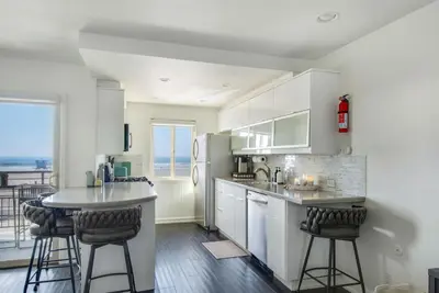 a kitchen with white cabinets and a counter with bar stools at Marina Del Mar 203A in Oceanside