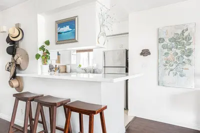 a kitchen with a counter and three stools at 5Br Retreat With Balcony And Patio, 2 Homes From Sand By Beachview Rentals in Newport Beach