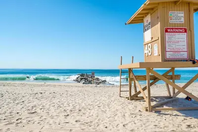a lifeguard station on a beach with the ocean at 5Br Retreat With Balcony And Patio, 2 Homes From Sand By Beachview Rentals in Newport Beach
