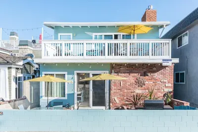 a house with a balcony and two umbrellas at Coastal 4Br Retreat, Just Steps From 44Th St Beach in Newport Beach