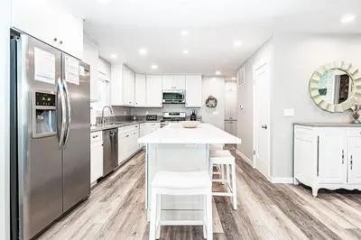 a kitchen with white cabinets and a stainless steel refrigerator at Coastal 4Br Retreat, Just Steps From 44Th St Beach in Newport Beach