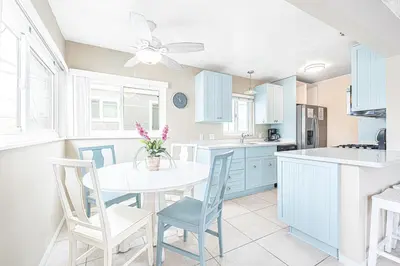 a kitchen with blue cabinets and a white table and chairs at Coastal 4Br Retreat, Just Steps From 44Th St Beach in Newport Beach