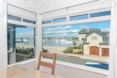 a room with a window with a view of the water at Bayfront 3Br With Harbor Views, Only Steps To The Beach By Beachview Rentals in Newport Beach