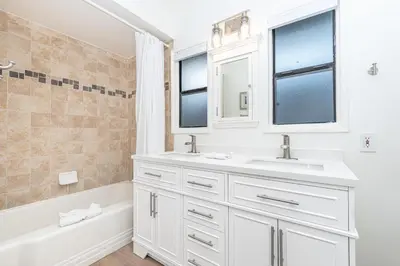 a white bathroom with a sink and a bath tub at Bayfront 3Br With Harbor Views, Only Steps To The Beach By Beachview Rentals in Newport Beach