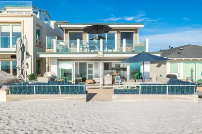 a house on the beach with a pool and umbrellas at 3Br Oceanfront Home W Patio Right On The Sand By Beachview Rentals in Newport Beach