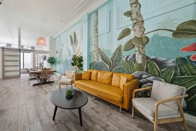a living room with a yellow couch and a mural at Downtown Gaslamp Getaway Stylish 4BR APT in San Diego