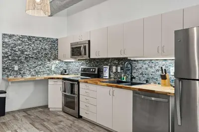 a kitchen with white cabinets and stainless steel appliances at Downtown Gaslamp Getaway Stylish 4BR APT in San Diego