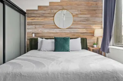 a bedroom with a large bed with a wooden wall at Downtown Gaslamp Getaway Stylish 4BR APT in San Diego