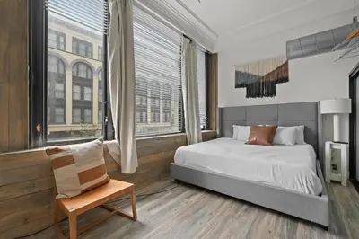 a bedroom with a bed and a chair and windows at Party in Gaslamp 4BR Downtown Pad with Bathtub in San Diego