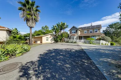 a house with a palm tree and a driveway at Private Hilltop Getaway with Patio Dogs Welcome! in Vista