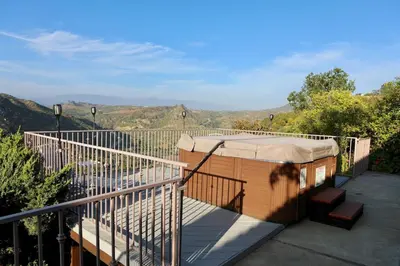 a hot tub on a balcony with mountains in the background at Quiet Hilltop Home With Stunning Hill Top And Valley Views in Valley Center