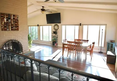 a living room with a table and chairs and a clock at Quiet Hilltop Home With Stunning Hill Top And Valley Views in Valley Center