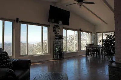 a living room with a table and chairs and windows at Quiet Hilltop Home With Stunning Hill Top And Valley Views in Valley Center