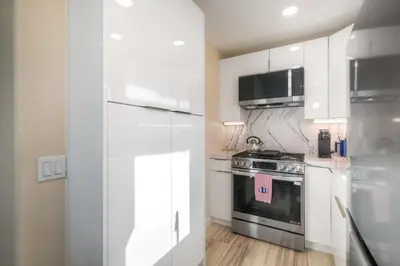 a kitchen with white cabinets and a stove and a microwave at Monarch Cove - Unit B For 2ppl in Oceanside