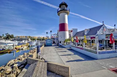 a lighthouse on a dock with boats in the water at Monarch Cove - Unit B For 2ppl in Oceanside