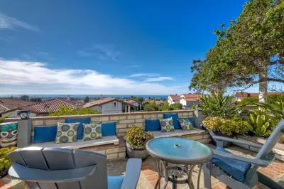 a patio with a table and chairs on a wall at Luxury Coastal Escape | Sleeps 4 | Ocean Views + Resort Amenities in Carlsbad
