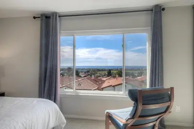 a bedroom with a bed and a chair and a large window at Luxury Coastal Escape | Sleeps 4 | Ocean Views + Resort Amenities in Carlsbad