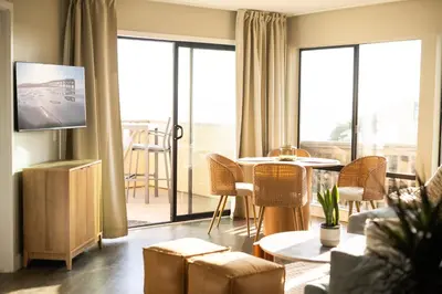 a living room with a tv and a table and chairs at Pier View Sunset - Ocean Front, Patios, Location, Views in San Diego