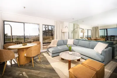 a living room with a blue couch and tables at Pier View Sunset - Ocean Front, Patios, Location, Views in San Diego