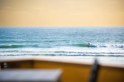 a person riding a wave on a surfboard in the ocean at Pier View Sunset - Ocean Front, Patios, Location, Views in San Diego