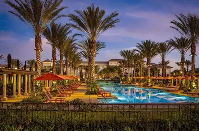a resort pool with chairs and palm trees at night at Irvine Spectrum 1 bed 1 bath in Irvine