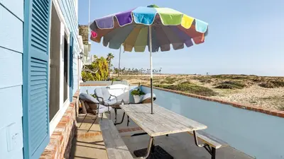 a patio with a table and an umbrella at Oceanfront Atelier by AvantStay Beachfront Balboa Peninsula Escape in Newport Beach