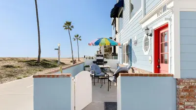 a house with a patio with a table and an umbrella at Oceanfront Atelier by AvantStay Beachfront Balboa Peninsula Escape in Newport Beach