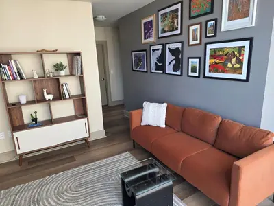 a living room with a brown couch and a shelf at Downtown Beautiful 3-bedroom Apartment Steps to Convention Center, Petco Park! in San Diego
