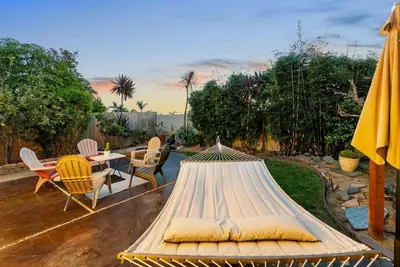a bed with pillows and a table and chairs at Serena Encinitas by Coastline Vacation Rentals in Encinitas