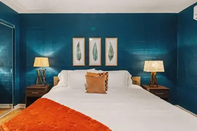 a blue bedroom with a large bed and two lamps at The Artist's Loft by Coastline Vacation Rentals in San Diego