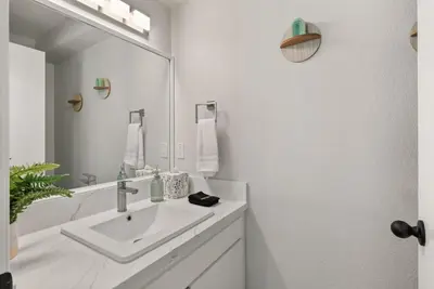 a white bathroom with a sink and a mirror at The Artist's Loft by Coastline Vacation Rentals in San Diego