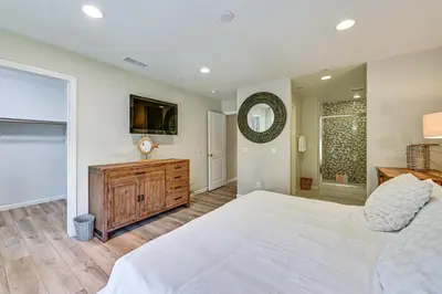 a bedroom with a large white bed and a flat screen tv at 1 Mi to Beach! San Clemente Gem with Rooftop Patios in San Clemente